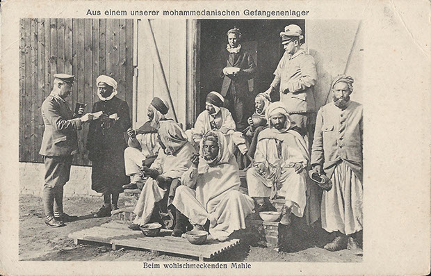 "Aus einem unserer mohammedanischen Gefangenenlager. Beim wohlschmeckendem Mahle". Ansichtskarte (Verlag S.& G. Saulsohn, Berlin), gelaufen als Feldpost im September 1918 von Zossen-Übungsplatz. Sammlung Detlev Brum. Das Foto wird mit der Bildunterschrift "Afrikanische Gefangene vor dem Mittagsmahl" verwendet in "Der Völkerzirkus unserer Feinde" (1917). Das Vorwort verfasste Leo Frobenius, einer der bedeutendsten deutschen Ethnologen, der zu Kriegsbeginn in geheimer Mission einen Aufstand im Sudan - damals faktisch eine britische Kolonie - organisieren sollte.