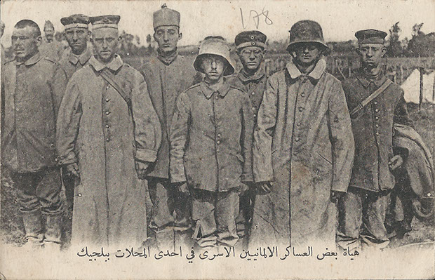 "Camp de prisonniers allemands en Belgique. – Différents types de soldats Allemands." Carte Postale, beschriftet, ohne Datum. Sammlung Detlev Brum. Der arabische Schriftzug entspricht dem französischen Text auf der Rückseite, übersetzt: "Gefangenenlager in Belgien. - Verschiedene Typen von deutschen Soldaten". Eine szenische Zusammenstellung von Kriegsgefangenen, deren Gesichtszüge und schlecht sitzende Bekleidung sie als Gegenteil von "Kultur und Zivilisation" kennzeichnen sollen. Eine Ansichtskarte für die Angehörigen in der Heimat, produziert für die arabisch-sprachigen Soldaten in der französischen Armee.