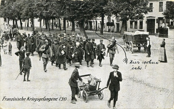 "Französische Kriegsgefangene" (Motiv mit gemischter Gruppe von Kriegsgefangenen, darunter Afrikaner). Ansichtskarte, gelaufen als Feldpost im Juni 1915 von Zossen an die Eltern in Lüneburg, offensichtlich mit einem Hinweis des Soldaten: "Hier wohne ich". Stempelabdruck: 4. Kampagnie Garde-Landsturm-Bataillon. Sammlung Markus Kreis.