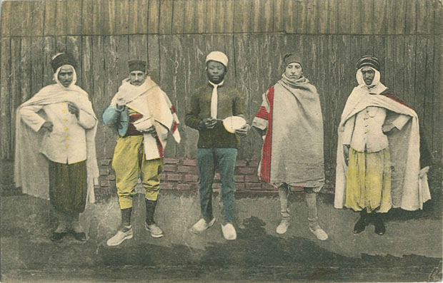 "Gefangenenlager Zossen-Wünsdorf". Ansichtskarte, gelaufen im Juni 1917 von Zossen als Feldpost. Sammlung Markus Kreis. Handschriftlich Rückseite: "Innigstgeliebte Mama und (unleserlich). Die herzlichsten Grüsse und Küsse sendet euch euer euch von Herzen liebender (unleserlich). In diesen Kleidern laufen die Gefangenen hier herum." Identische (s/w-) Ansichtskarte, gelaufen von Zossen im Dezember 1916 als Feldpost.