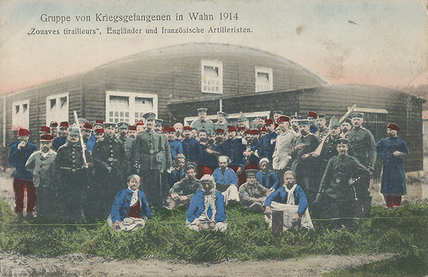 "Gruppe von Kriegsgefangenen in Wahn 1914. „Zouaves tirailleurs“, Engländer und französische Artilleristen". Verlag Karl Rud. Bremer & Co., Köln a. Rh., Neusserstr. 28. Mit Genehm. d. kgl. Gouvernements d. Festung Köln. Ansichtskarte, gelaufen als Feldpost im Oktober 1914 von Wahn (Schiessplatz). Sammlung Detlev Brum. Die Ansichtskarte, von der es mindestens eine weitere Version gibt, wird bereits im Oktober 1914 als Feldpost versendet, so dass afrikanische Soldaten praktisch unmittelbar nach Kriegsbeginn in die Gefangenschaft nach Köln kamen. Wie auch auf einigen anderen Karten werden die afrikanischen Gefangenen "pittoresk" in den Vordergrund gestellt.