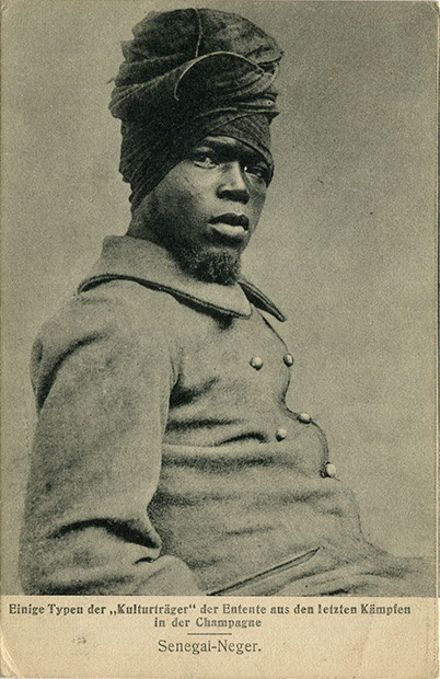 "Senegal-Neger. Einige Typen der „Kulturträger“ der Entente aus den letzten Kämpfen in der Champagne". Ansichtskarte, gelaufen als Feldpost von der Front an die Mutter im April 1918 (Stempelabdruck: Sturmbatallion 14, 1. Sturmkompagnie). Kunstverlag P. Maas & Sohn, Metz. Sammlung Markus Kreis. Am 16. April 1917 begann die Offensive in der Champagne, an der auch das von General Mangin kommandierte Zweite Kolonialkorps teilnahm, dem unter anderem 35 westafrikanische Bataillone angehörten. Die am folgenden Tag von den Deutschen gestartete Gegenoffensive führte auf französischer Seite zu enormen Verlusten. Besonders betroffen war das Zweite Kolonialkorps: Von den eingesetzten westafrikanischen Soldaten kamen 45% ums Leben. Beim II. Kolonialkorps kam es in der Folge zu kollektiven Gehorsamsverweigerungen. Von 554 Todesurteilen durch Militärgerichte wurden 49 durch Erschießungskommandos vollzogen.