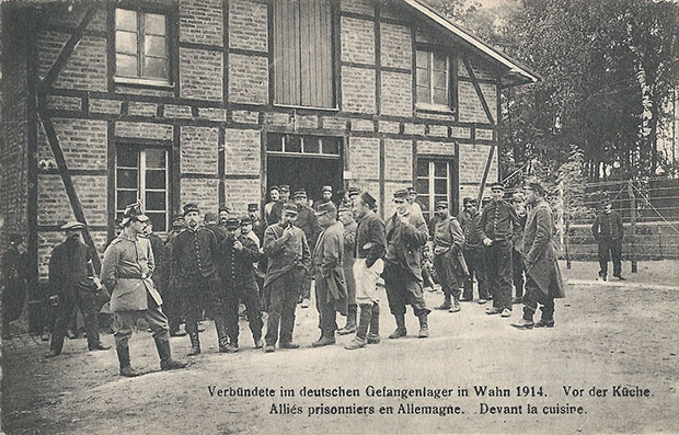 "Verbündete im deutschen Gefangenenlager in Wahn 1914. Vor der Küche. Alliés prisonniers en Allemagne. Devant la cuisine". N. Sch. Brux. – Reprod. Interd. – Autor. Par le gouv. Allemand, Brux.. Carte Postale, ungelaufen. Sammlung Detlev Brum. Bildidentische Ansichtskarte „Kriegsgefangene in Wahn. Ruhepause nach der Mahlzeit.“, wurde gesendet aus Wahn als Feldpost im Dezember 1914. Die zweisprachige Version ist vermutlich eine Ansichtskarte, die speziell für Kriegsgefangene angefertigt wurde, die solche Ansichtskarten in die Heimat verschickten. Wie auch bei anderen Ansichtskarten wurde ein ebenso "pittoresker" wie gut gekleideter und wohlgenährter Nordafrikaner in den Vordergrund gestellt, um in der Heimat der Kriegsgefangenen den Eindruck guter Behandlung in deutschen Kriegsgefangenenlagern zu erwecken.