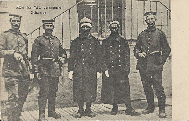 "Zwei vor Metz gefangene Schwarze". Ansichtskarte, Verlag F. Conrard, Metz, Sammlung Weltkrieg. Ungelaufen, handschriftliche Notiz auf der Rückseite "Zur Erinnerung an den Krieg 1914/17". Sammlung Detlev Brum. Für die Gefangennahme von schwarzafrikanischen Soldaten sollen Prämien ausgesetzt worden sein. Sie waren beliebte Fotoobjekte, für das private Erinnerungsalbum einerseits, für die deutsche Kriegspropaganda andererseits. Die Betextung der Fotos fällt dabei durchaus uneinheitlich aus und changiert zwischen dem neutral verwendeten "Schwarze" und dem rassistisch-abwertenden "N....", wobei letzteres in der Regel mit weiteren spezifischen Inszenierungen einhergeht.