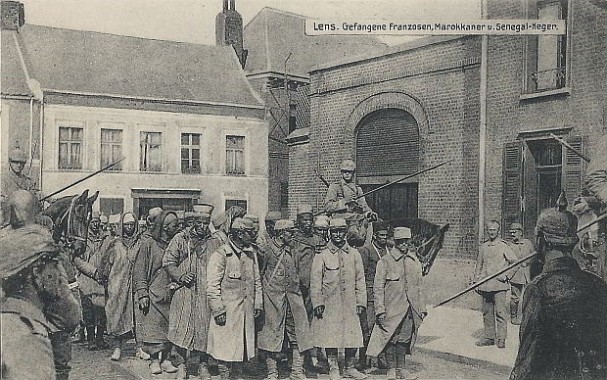 "Lens. Gefangene Franzosen, Marokkaner u. Senegal-Neger". Kunst- und Verlagsanstalt Schaar & Drathe, Trier. Ansichtskarte, ungelaufen. Sammlung Detlev Brum. Alliierte Kriegsgefangene beinahe täglich zur Schau gestellt, um die Moral der einheimischen Bevölkerung zu schwächen.