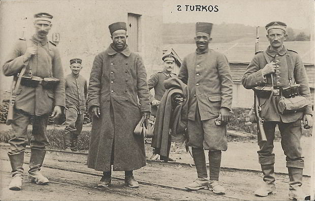 "2 Turkos". Ansichtskarte, ungelaufen, keine weiteren Angaben. Sammlung Detlev Brum. Die Ansichtskarte zeigt gefangene nordafrikanische Soldaten (allgemein als "Turkos" bezeichnet). In der Frühphase des Krieges erzeugte die Gefangenennahme von afrikanischen Soldaten große Aufmerksamkeit und manche deutsche Soldaten schmückten mit den Fotos oder Ansichtskarten ihr Kriegserinnerungsalbum.