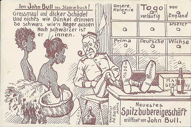 "Dem John Bull ins Stammbuch! Grossmaul und dicker Schädel – Und nichts wie Dünkel drinnen – So schwarz wie’n Neger aussen – Noch schwärzer ist er innen." Postkarte, gelaufen als Feldpost im September 1914. Sammlung Detlev Brum. Die deutsche Kolonie Togo wurde bereits Ende August 1914 von französischen und britischen Truppen besetzt. Der englische "Krämer" (eine der typischen deutschen Propagandadarstellungen, die stets ein unsauberes Geschäftsgebahren unterstellt) übernimmt das deutsche Geschäft und macht daraus ein Spitzbubereigeschäft, Alkohol auf dem Tisch und unter dem Stuhl. Die beiden Afrikaner*innen werden mit allen kolonialrassistischen Verzerrungen dargestellt.